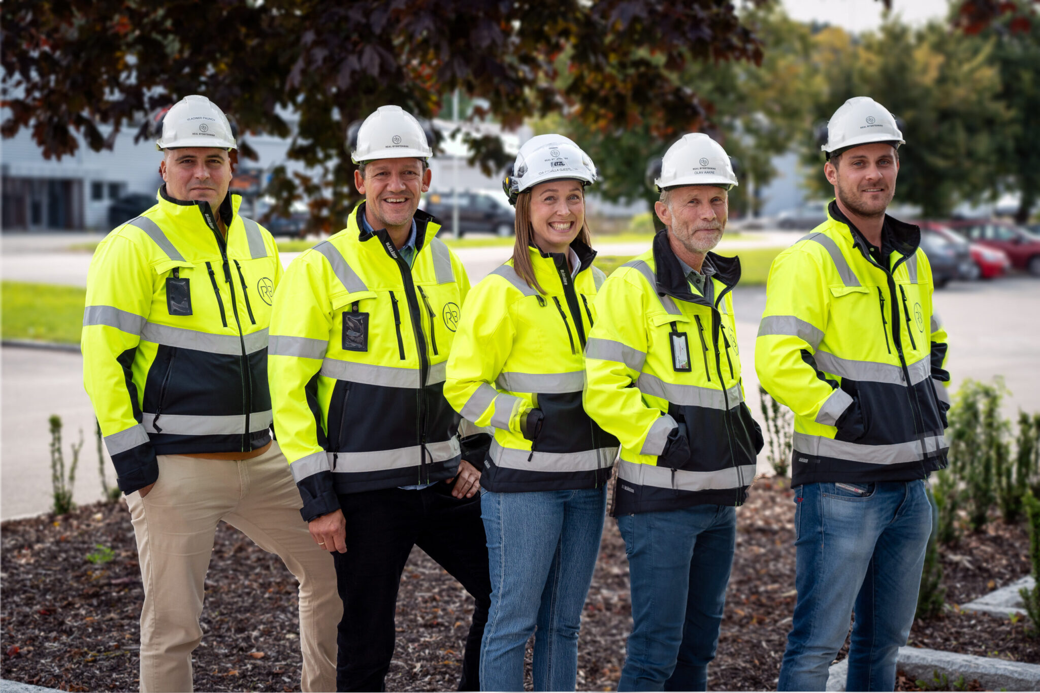 Gruppebilde av ansatte i Real Byggteknikk. De har på seg hjelm og refleksjakker